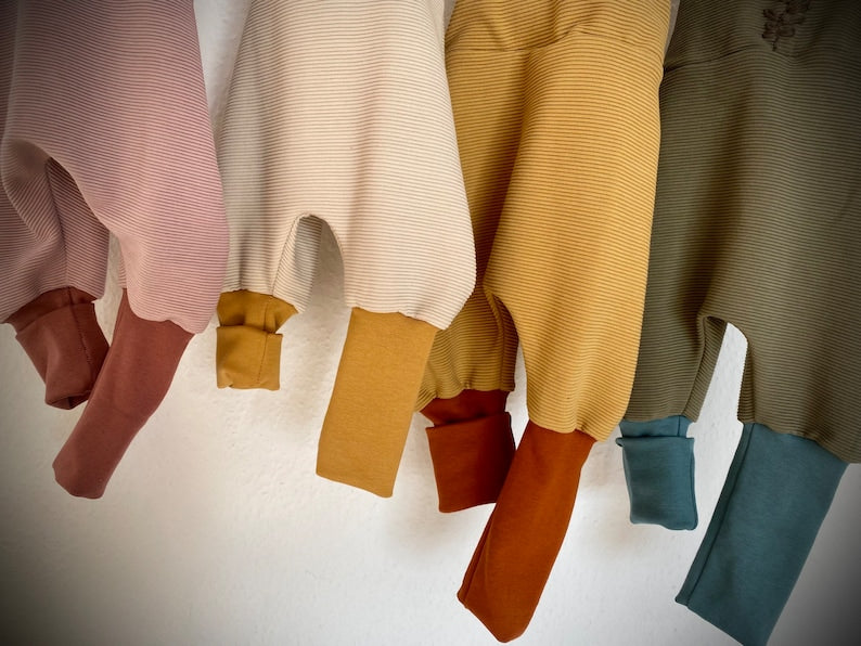Vier Knickerbockerhosen für Kleinkinder. Aufnahme der Hosenbeine in verschiedenen Farben (rosa, beige, gelb und olive).